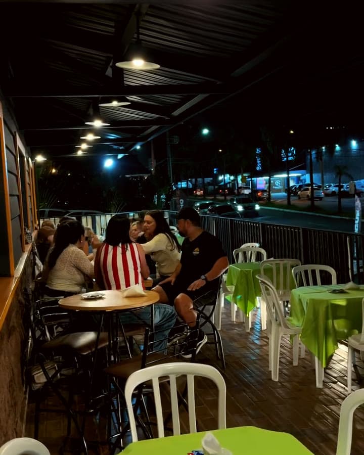 A varanda da Beef à noite, com as luzes acesas e as mesas na calçada da avenida